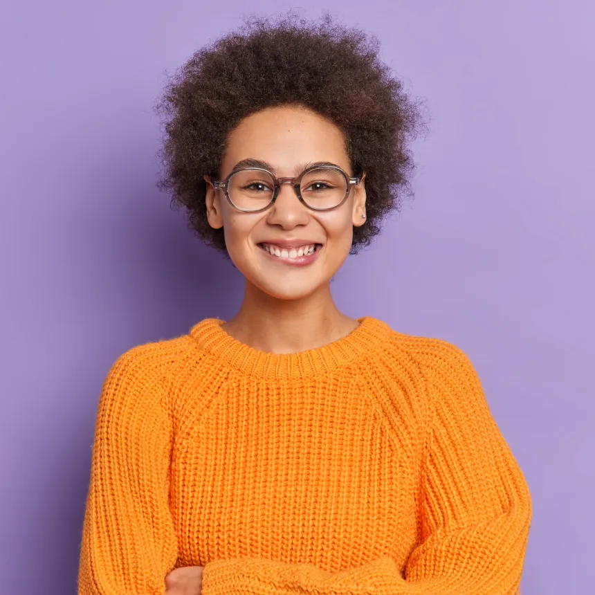 Smiling woman with curly hair and yellow sweater, testimonial photo